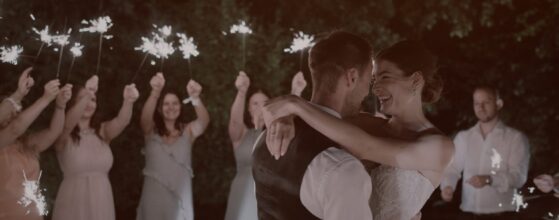Patricia und Josef gehen nach der Trauung durch das Spalier ihrer Gäste beim Berghotel Tulbingerkogel, alle klatschen und feiern – ein fröhlicher Moment aus ihrem Hochzeitsfilm.