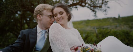 Caroline und Peter sitzen Arm in Arm am Hügel unterhalb von Schloss Spitz in der Wachau, festgehalten in einem emotionalen, cineastischen Hochzeitsfilm-Teaser.