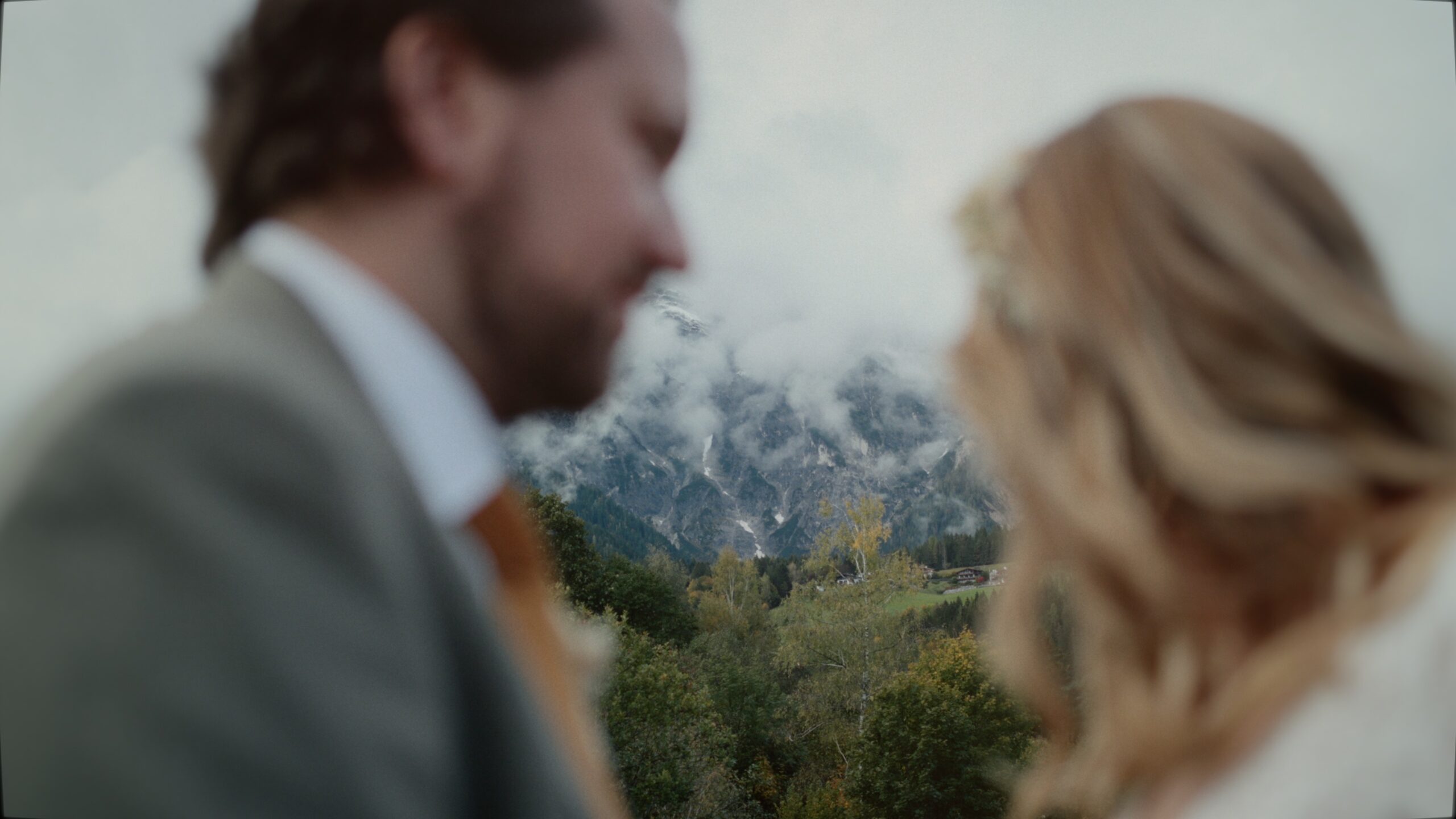 Jessica und Kevin teilen einen ruhigen Moment vor dem Der Kirchenwirt in Leogang, umgeben von den Salzburger Bergen.