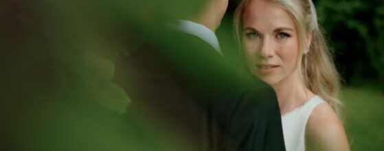 Johanna sieht Paul durch das Grün im Garten der Villa Weiss am Attersee an – ein intimer Moment ihres Hochzeitsfilms.