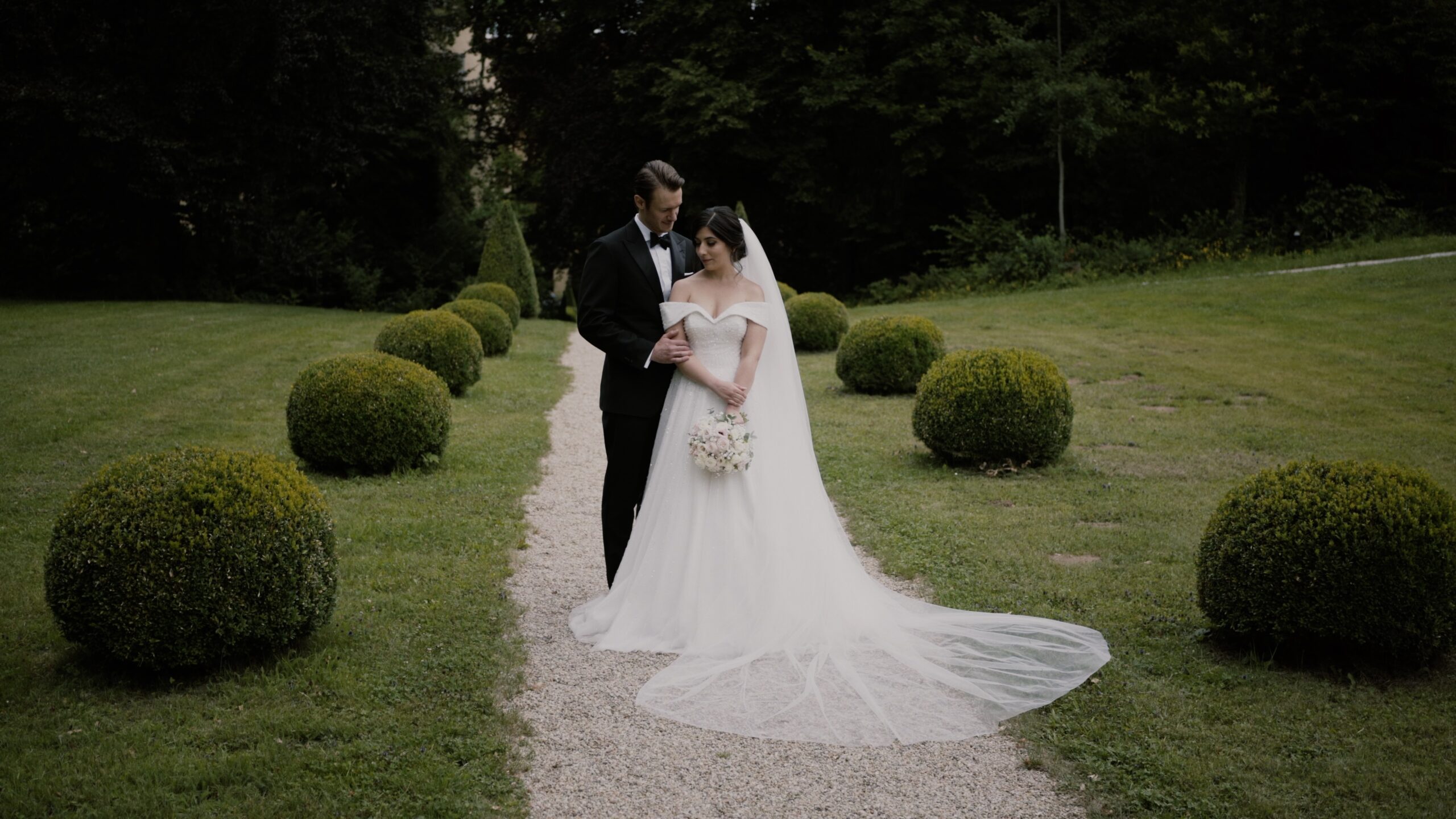 Maral und Raphael sitzen gemeinsam in den Gärten von Schloss Obermayerhofen während ihrer romantischen Hochzeit.